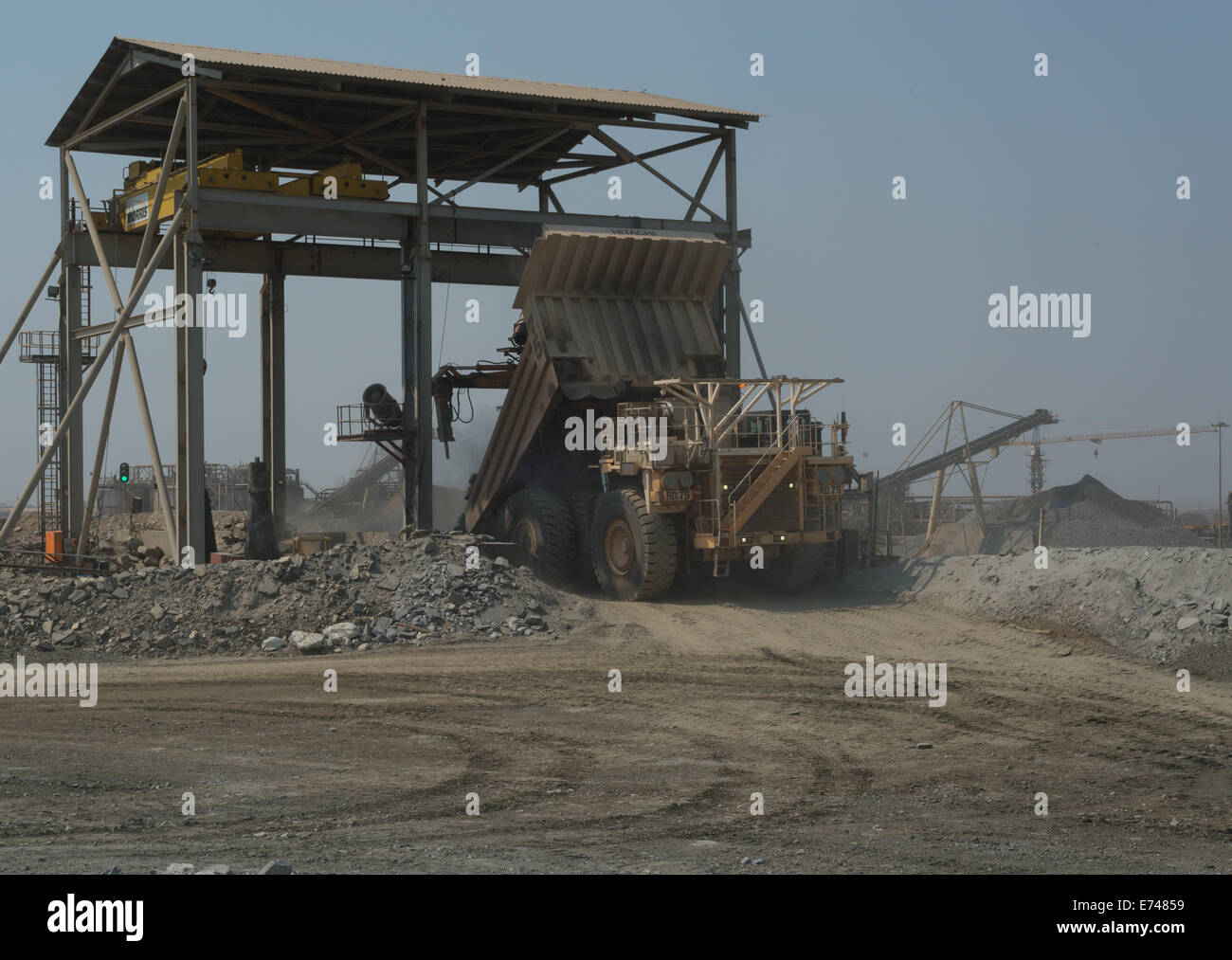 Un grand camion blanc Hitatchi déverse une charge de minerai dans le concasseur à une grande mine de cuivre de l'Afrique de l'ouvert. Banque D'Images