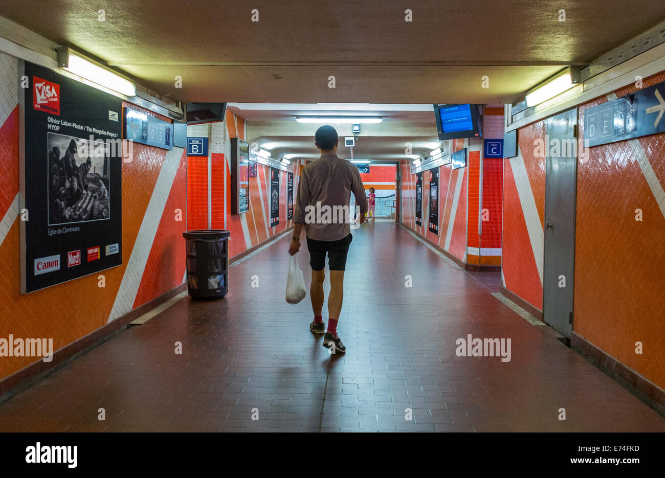 Perpignan, France, homme, portant sac à provisions en plastique, marcher à l'intérieur du tunnel dans la gare française, affiches de voyage ferroviaire, panneaux d'affichage mur de la station de gens Banque D'Images