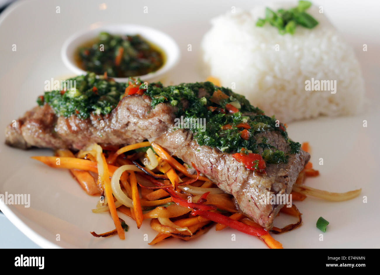 Viande avec chimichurri servi sur un lit de légumes et riz blanc dans un restaurant. Banque D'Images