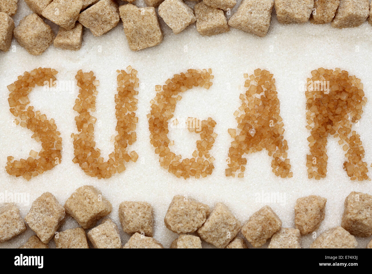 Le mot 'sugar' écrit avec la canne à sucre sur le sucre blanc et le sucre de canne brun fond cubes. Close-up. Banque D'Images