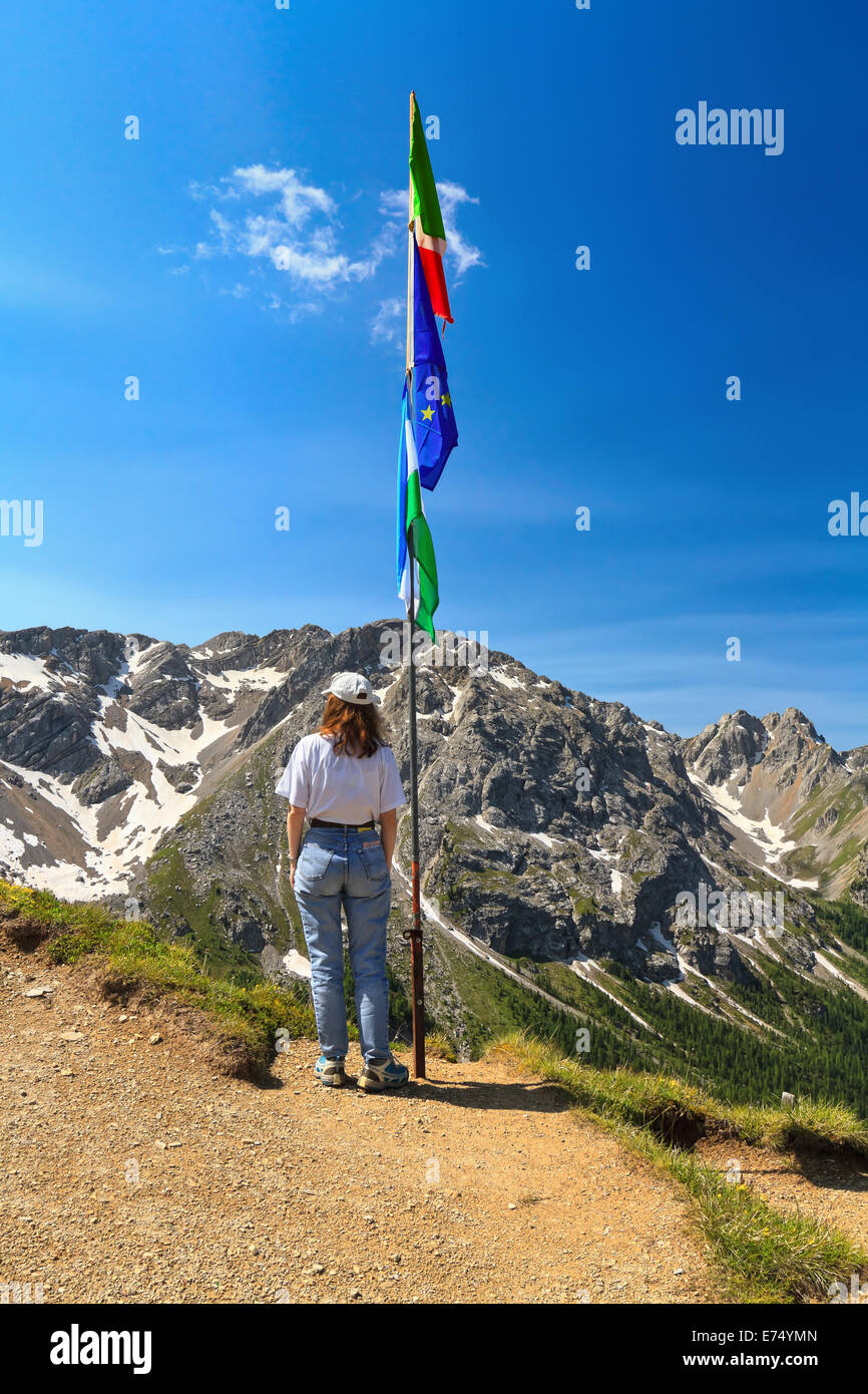 Femme sur point panoramique avec des drapeaux à San Nicolò passer avec Costabella ridge sur arrière-plan, le Trentin, Italie Banque D'Images