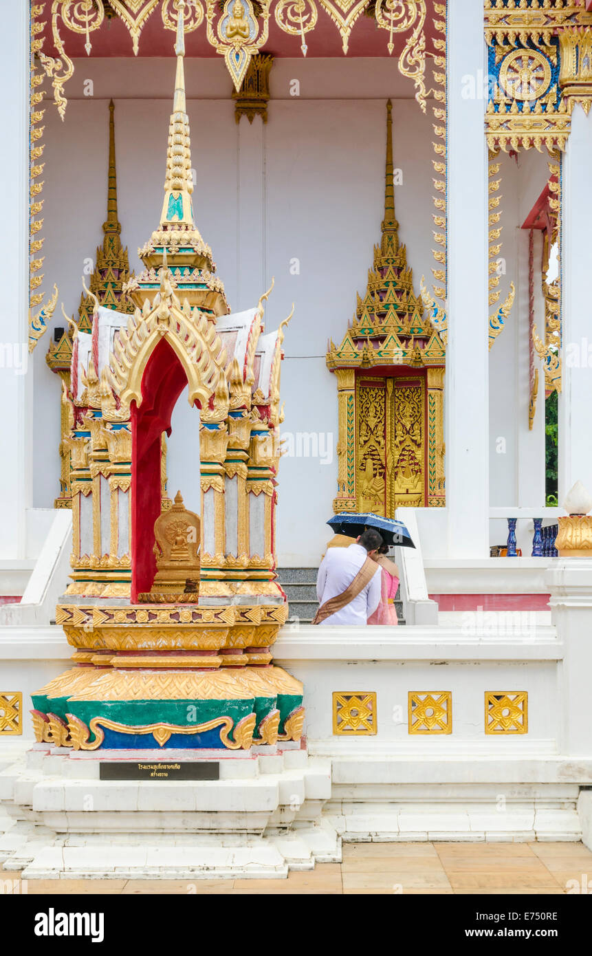 Un couple à l'abri sous un parapluie à Wat Karon Karon, l'île de Phuket, Thaïlande Banque D'Images