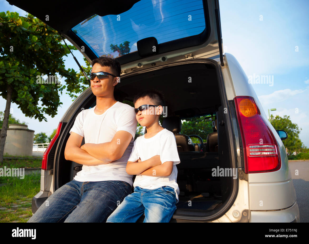 Petit garçon et père assis sur leur voiture dans le parc Banque D'Images