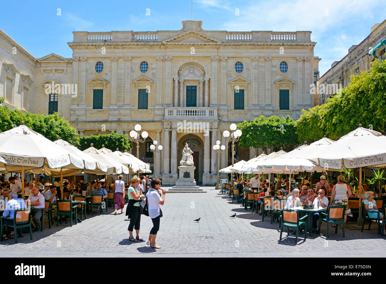 Des rangées de parasols blancs ombrageant des clients de café chaud en plein air Republic Square Bibliothèque nationale maltaise et statue de la reine Victoria Valletta Malte Banque D'Images