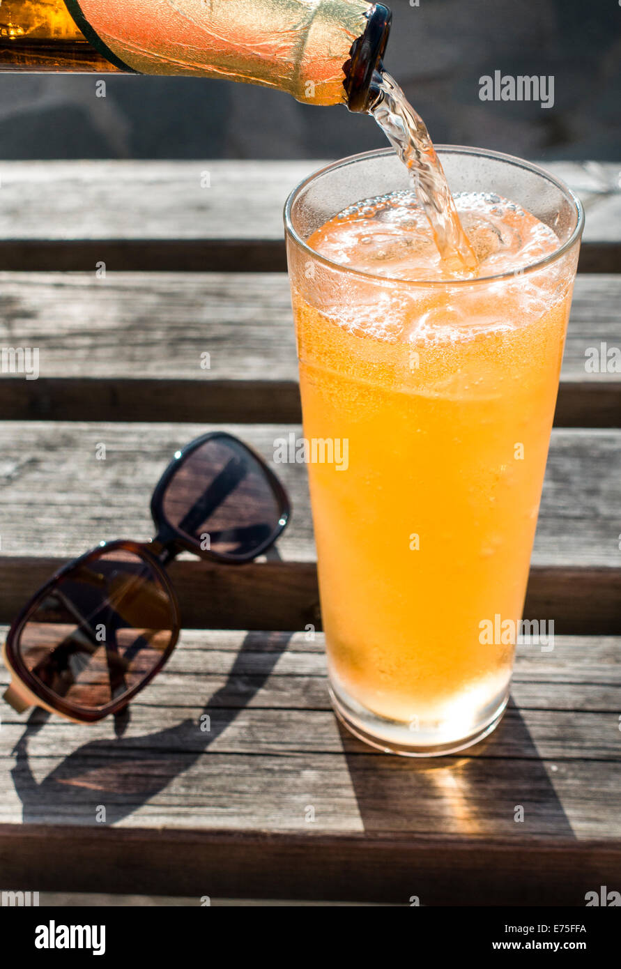 Orange rafraîchissante boisson froide est versé dans un verre sur glace Banque D'Images