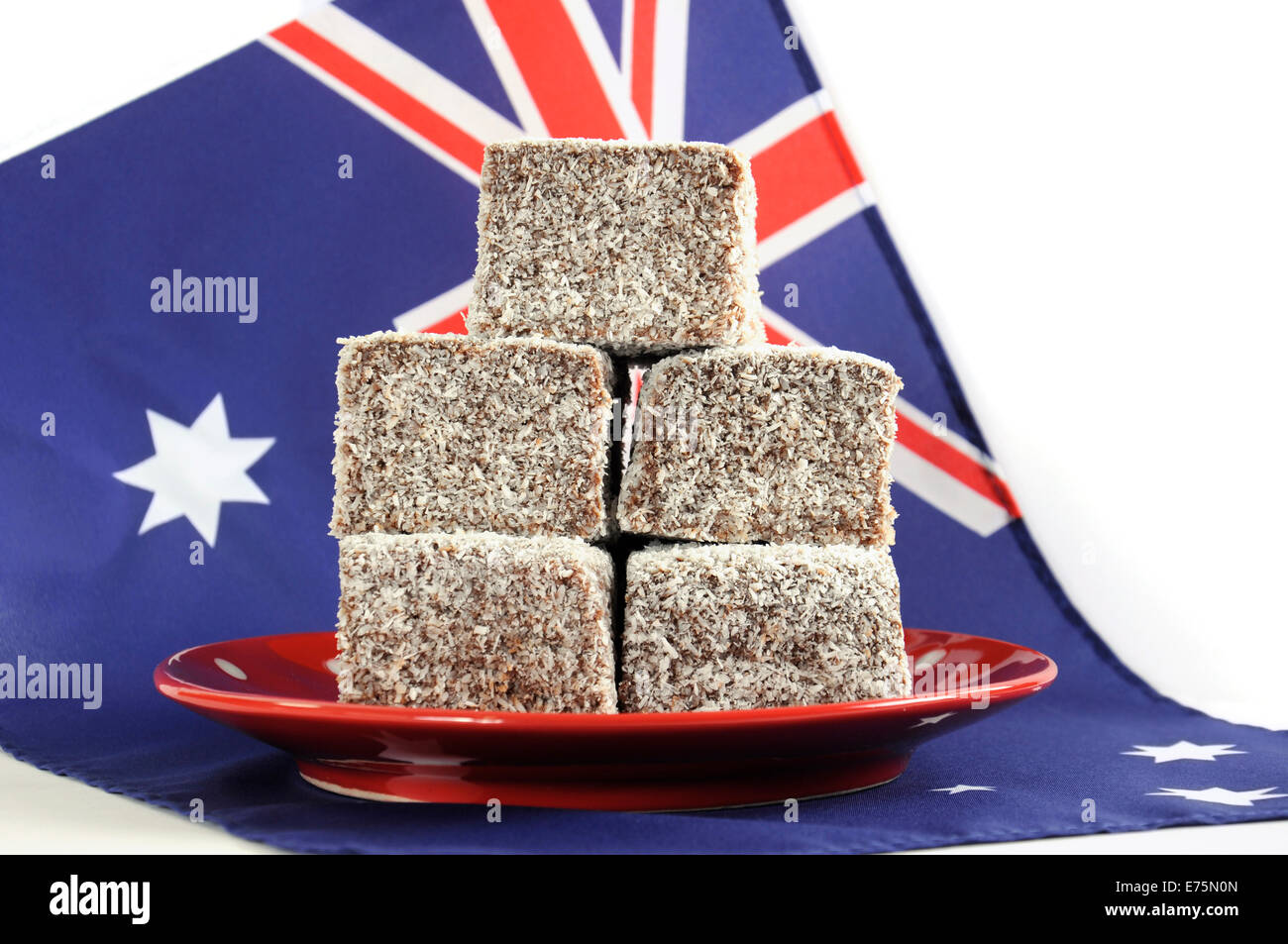 Gâteau traditionnel Australien, Lamingtons, sur la plaque rouge à pois avec drapeau australien sur un fond blanc. Banque D'Images