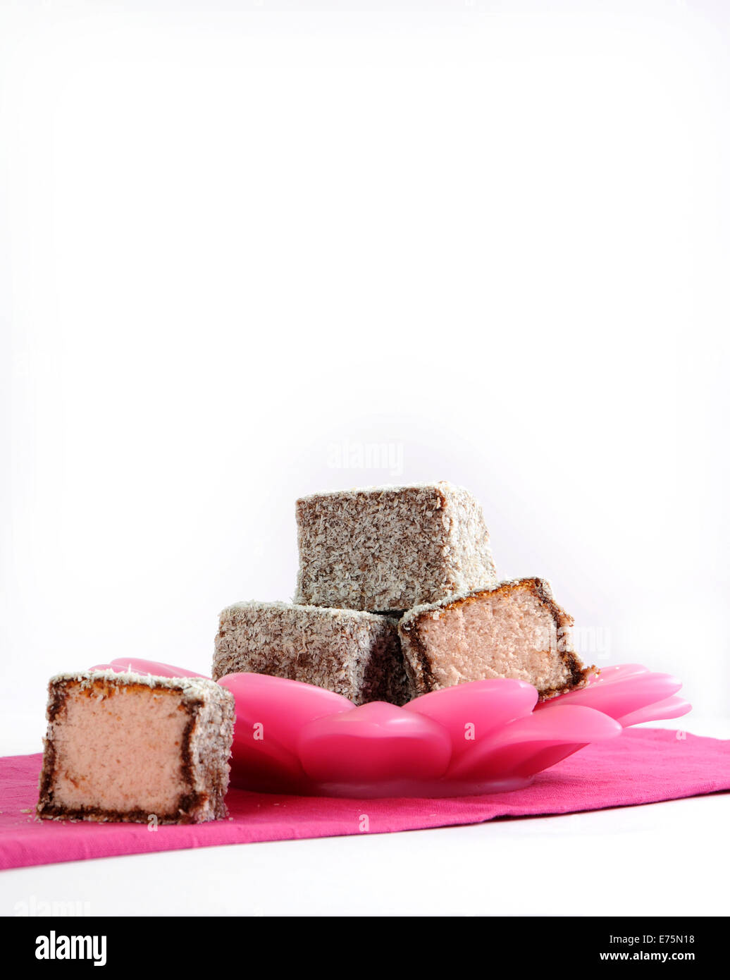 Gâteau traditionnel Australien, Lamington, sur la plaque et serviette rose sur un fond blanc. Banque D'Images