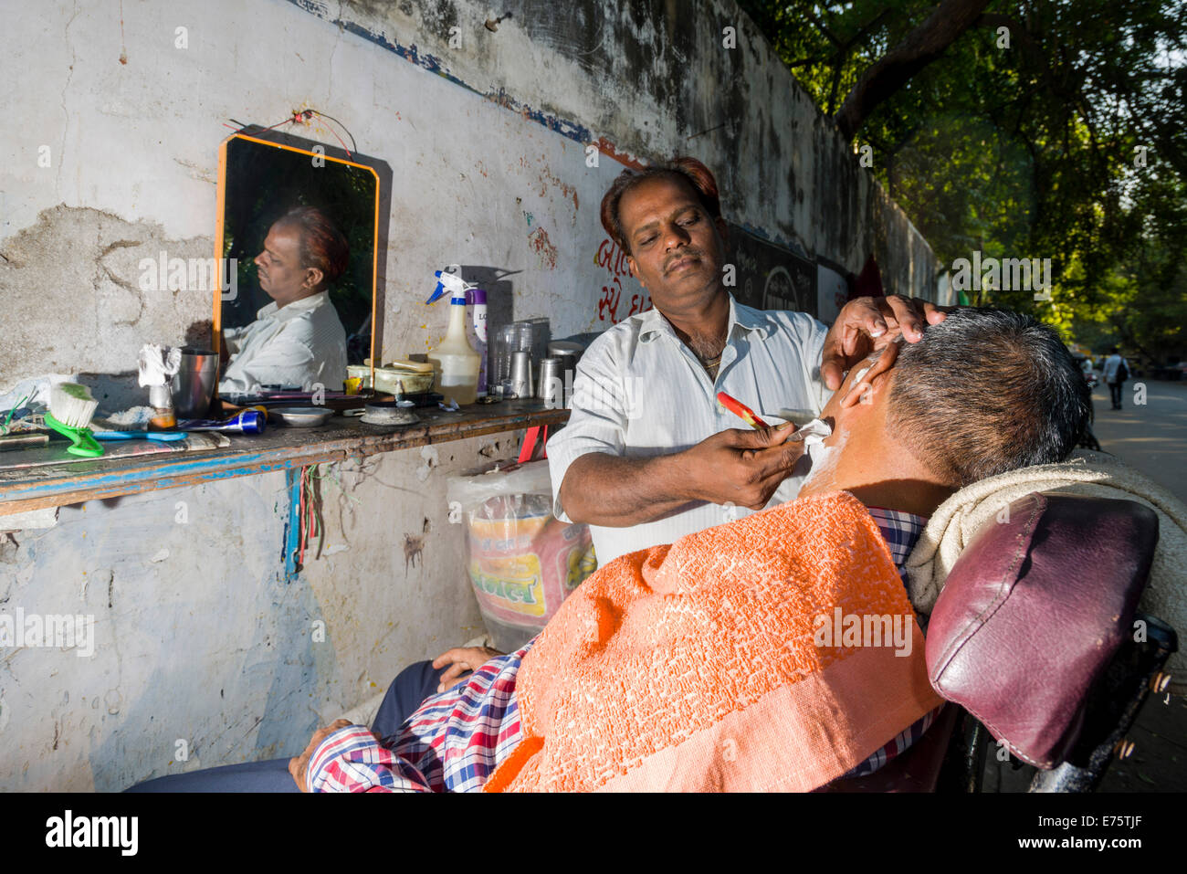 Un salon de coiffure est un client de rasage à sa boutique plein air, Ahmedabad, Gujarat, Inde Banque D'Images