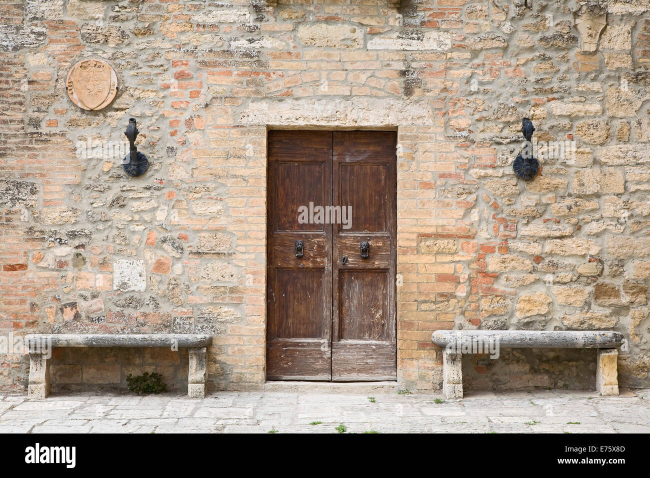 Deux bancs de pierre debout à côté de la porte d'une maison ancienne, Lucignano d'Arbia, Toscane, Italie Banque D'Images