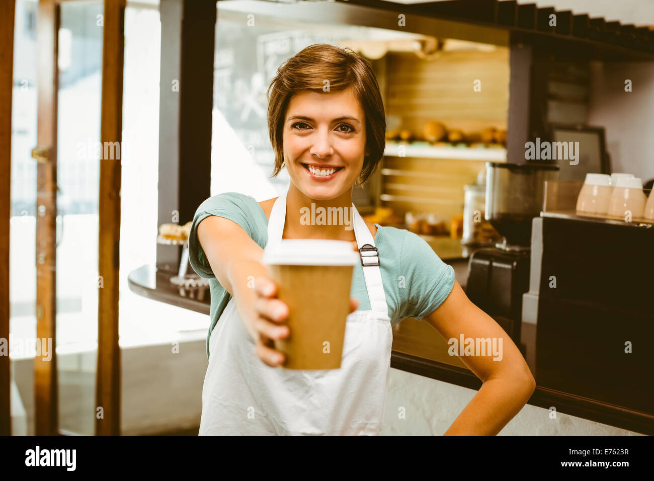 Barista Pretty smiling at camera holding disposable cup Banque D'Images