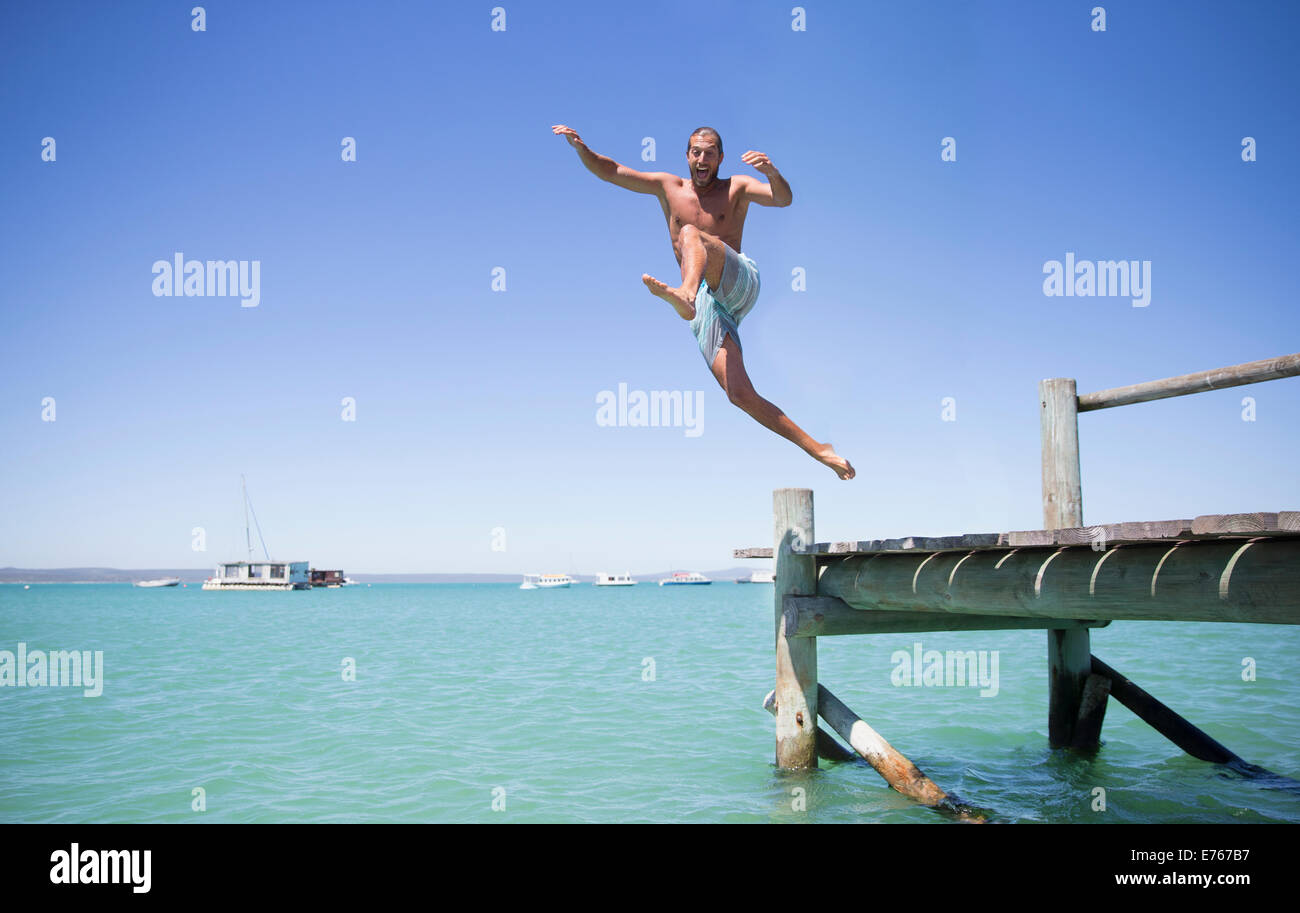 Couple Jumping off dock en bois dans l'eau Banque D'Images