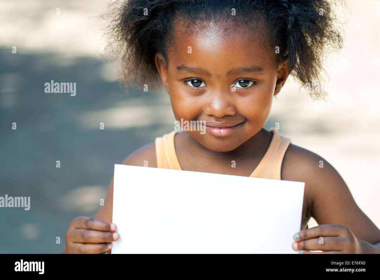 Close up portrait of cute African girl holding blank carte blanche à l'extérieur. Banque D'Images