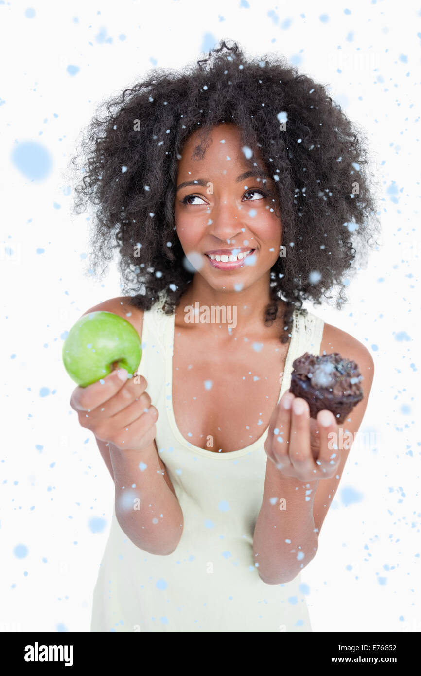 Image composite de jeune femme à la recherche jusqu'à demander de l'aide pour choisir entre un fruit et chocolat Banque D'Images