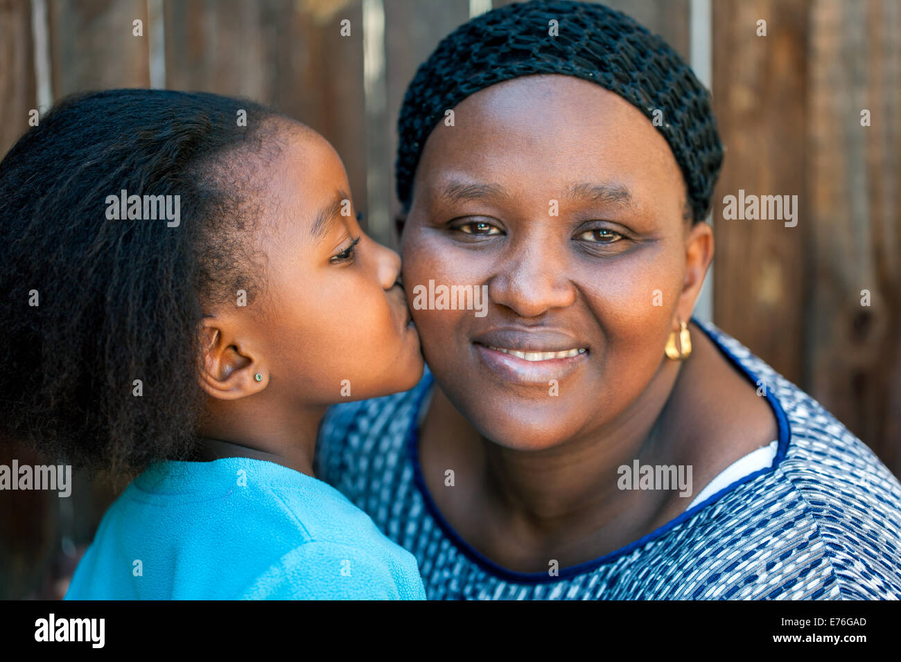 Close up portrait of little girl kissing mother on joue à l'extérieur. Banque D'Images