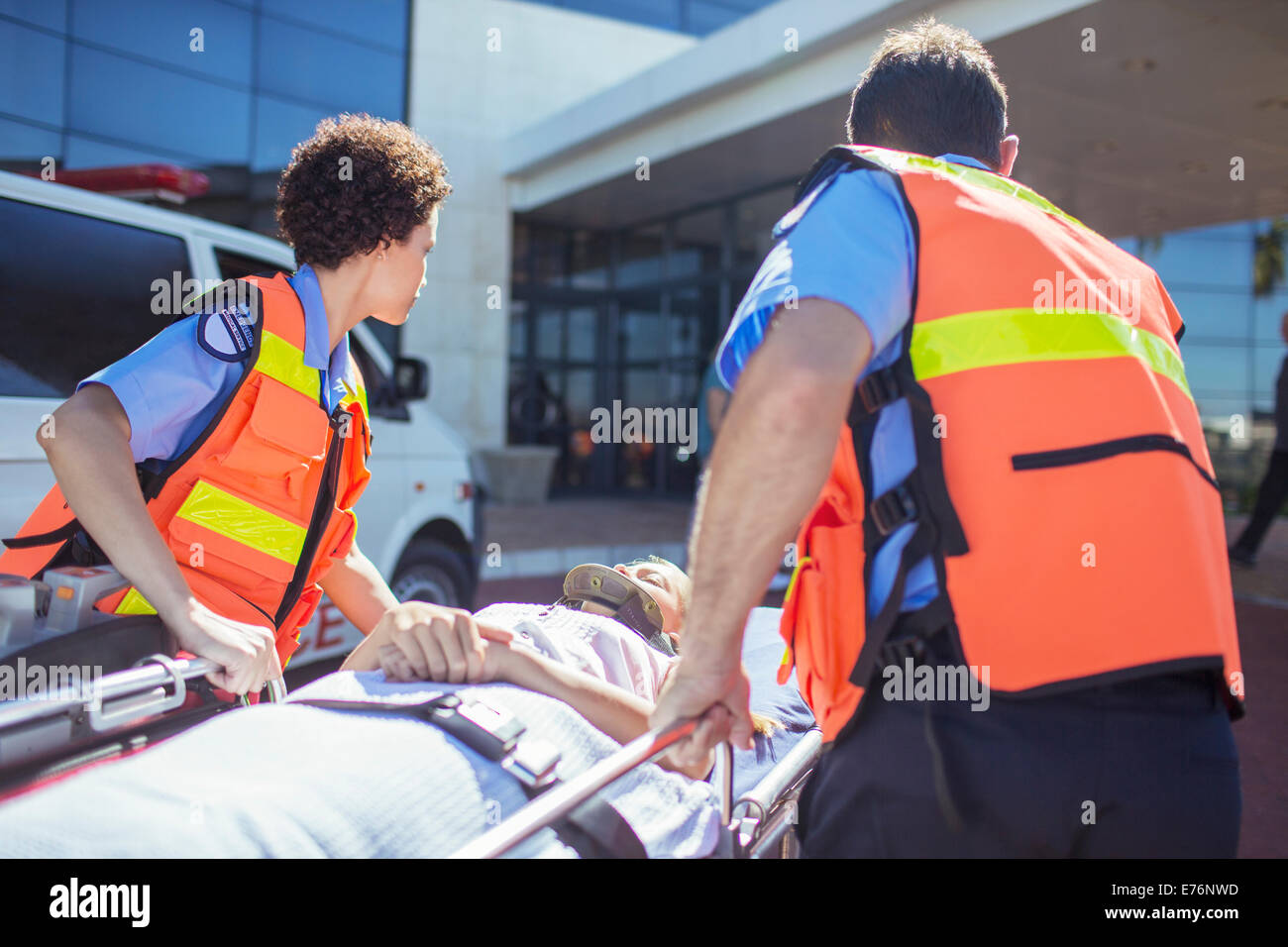 Les ambulanciers wheeling patient dans le stationnement de l'hôpital Banque D'Images