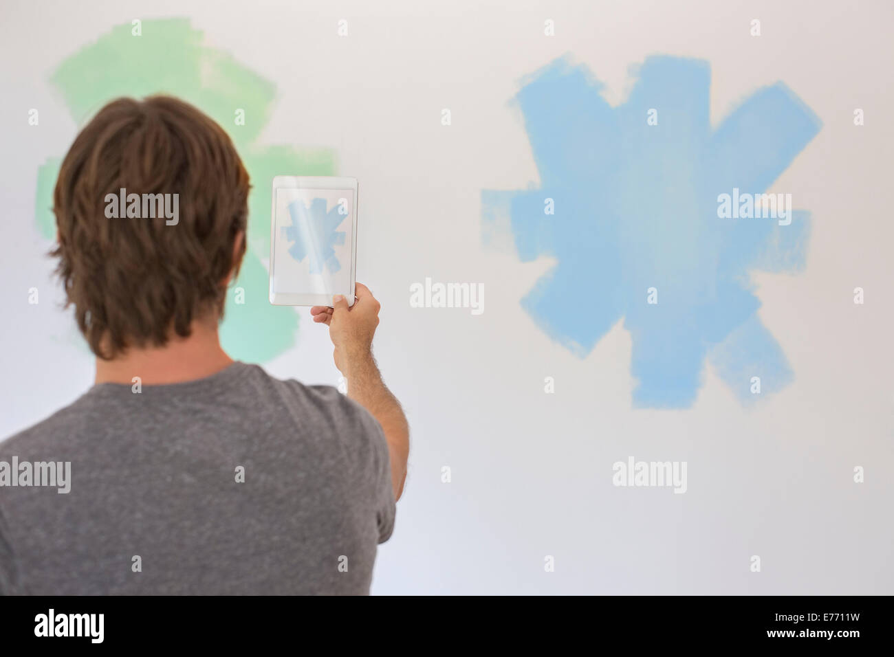Man taking photo of wall with digital tablet Banque D'Images