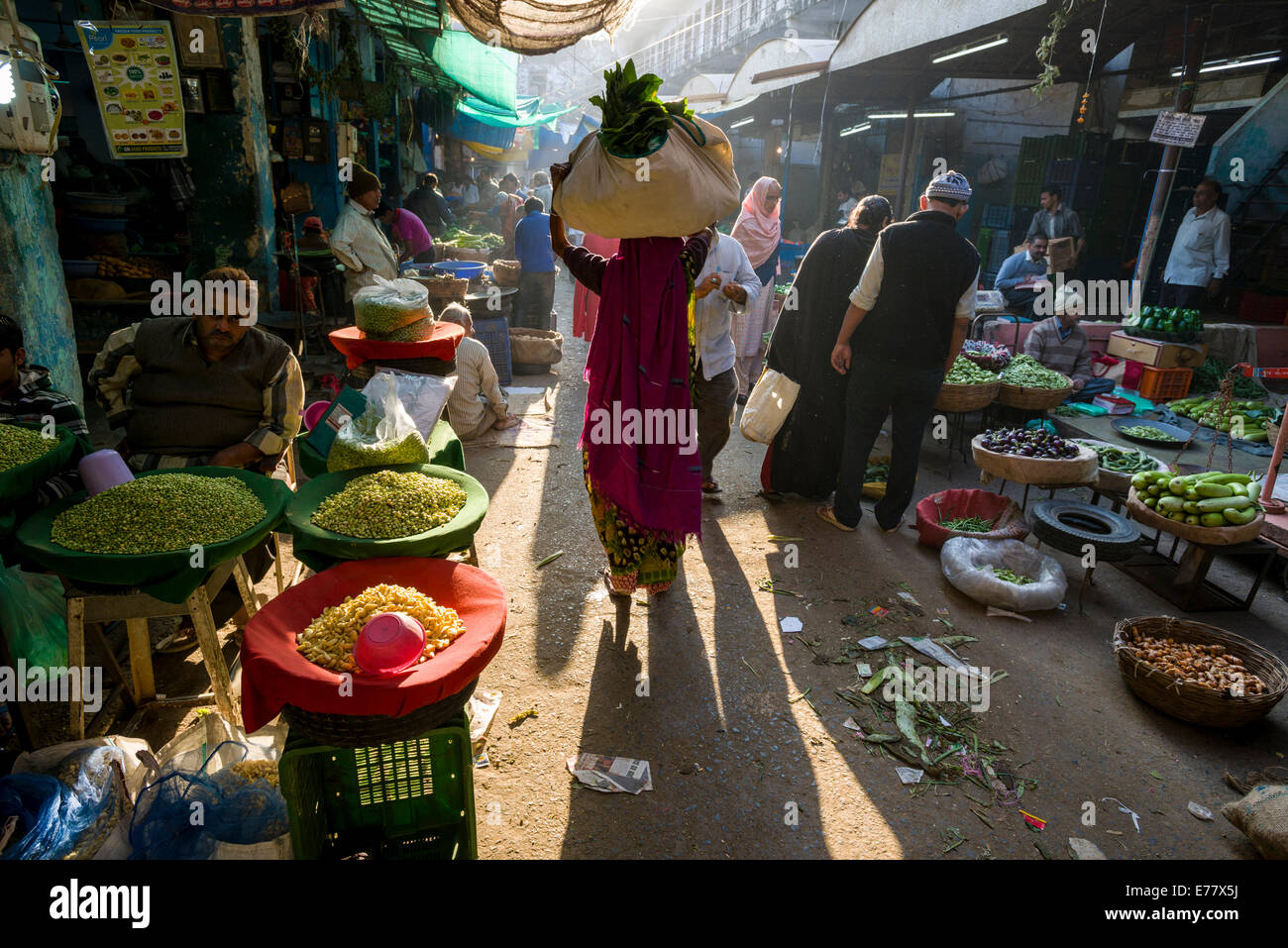 Une femme porte un sac avec des légumes sur la tête par le marché aux légumes, Ahmedabad, Gujarat, Inde Banque D'Images