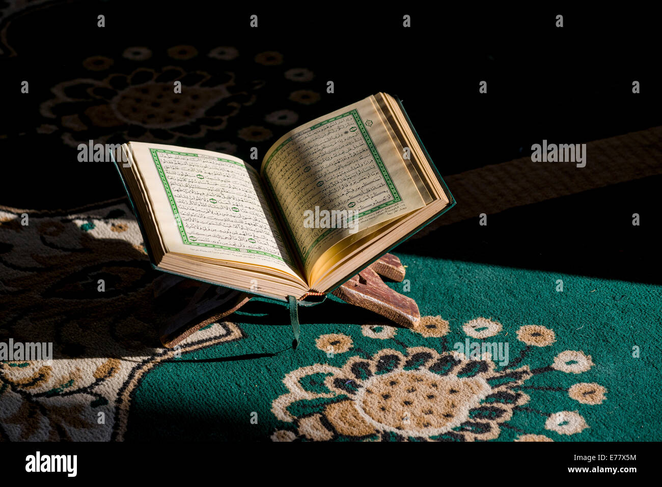 Le livre saint de l'Islam, le Coran, qu'ran, est ouvert à lire dans un rack debout sur un tapis vert à l'intérieur de la Mosquée Sidi Saiyyed Banque D'Images
