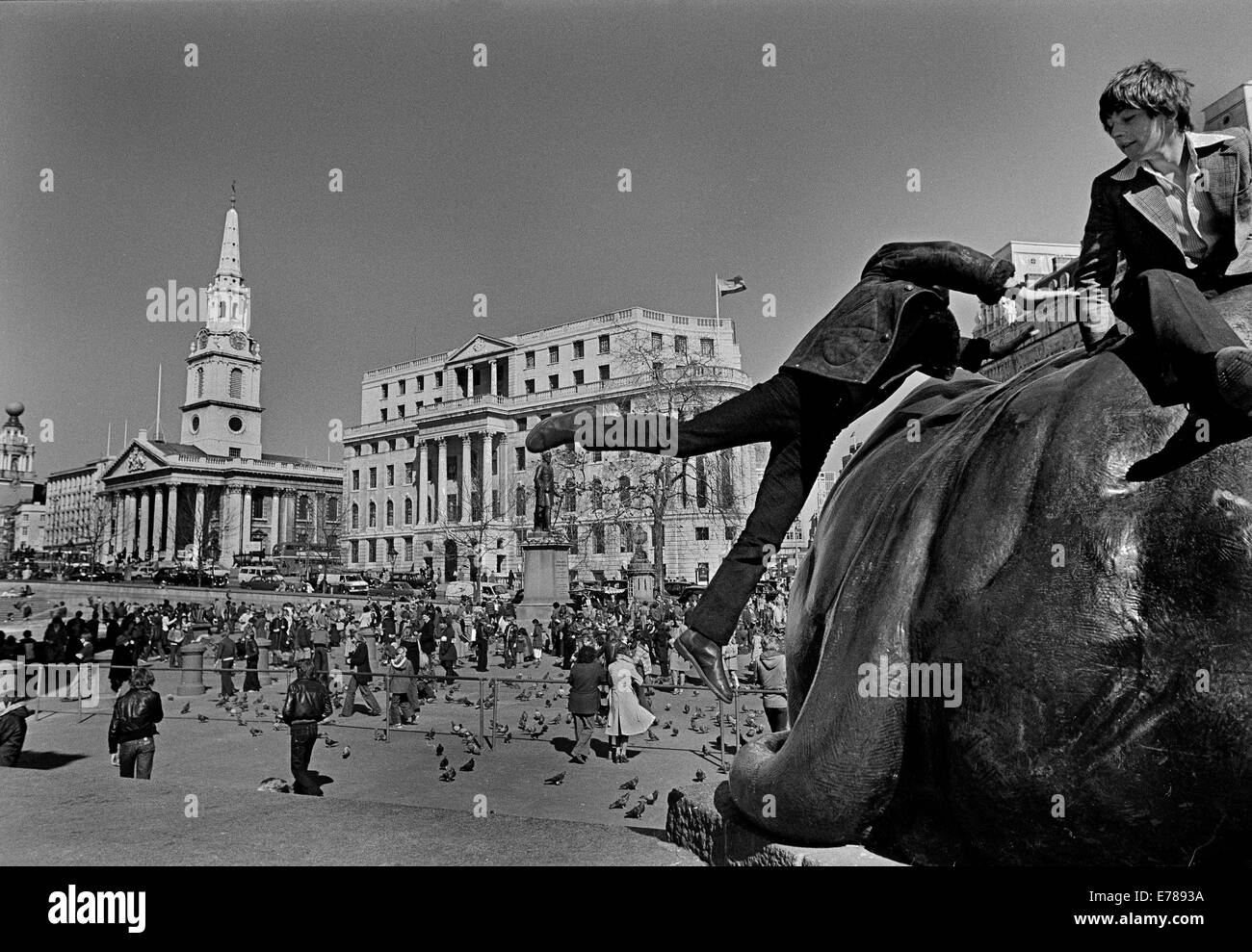 Garçon sautant sur lion statue, Trafalgar Square, Londres, Trafalgar Square est un espace public dans le centre de Londres Banque D'Images
