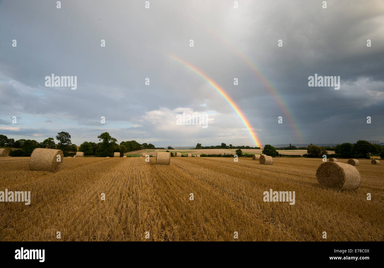 Lumière du soir orageux et un double arc-en-ciel dans un champ de bottes de foin, Stanton par Dale dans le Derbyshire Banque D'Images