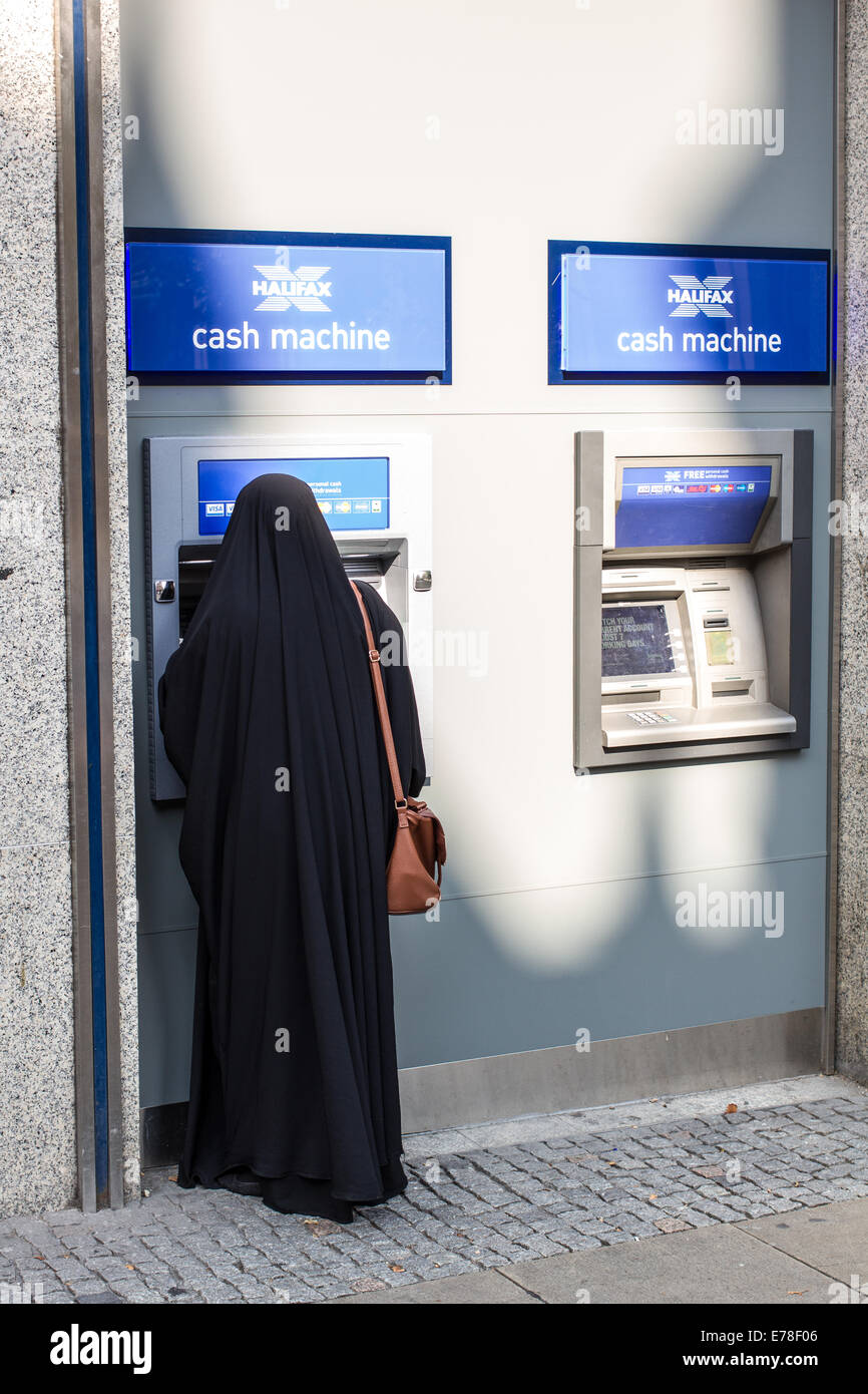 Une femme dans une burqa à l'aide d'un distributeur automatique de billets à Sheffield UK Banque D'Images