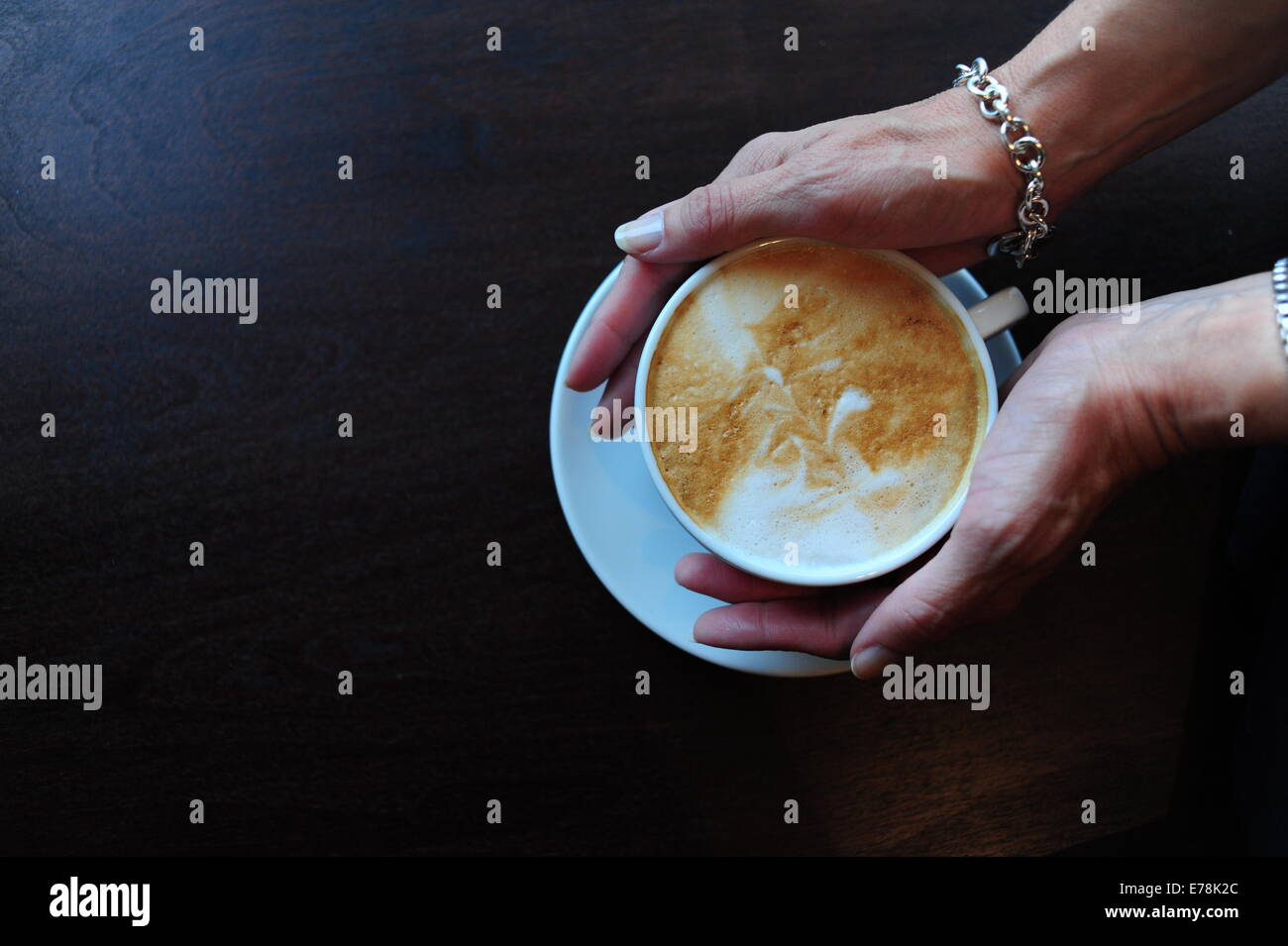 Mature Woman in cafe tenant une tasse de café cappuccino sur head voir Banque D'Images