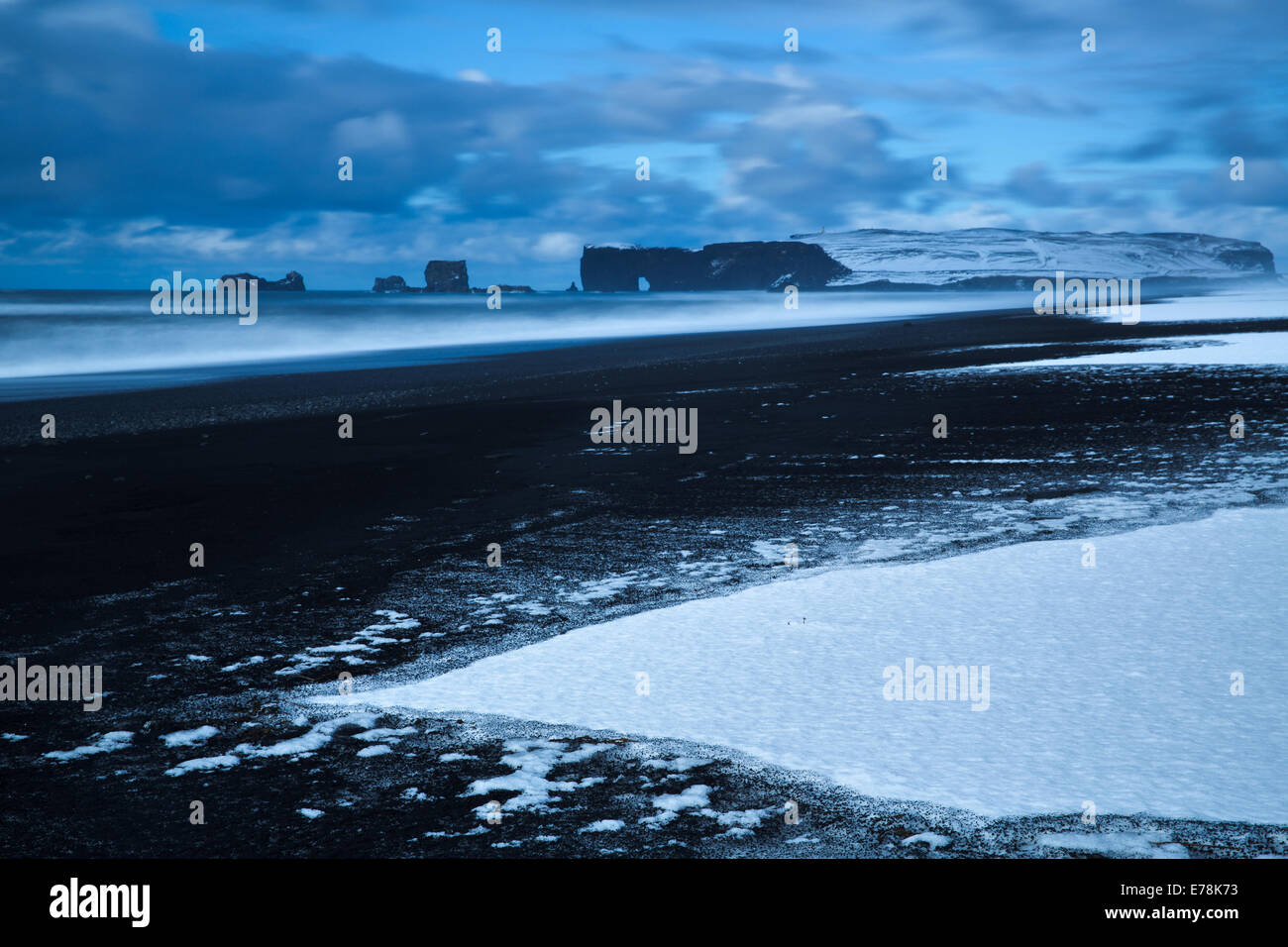 La vue le long de la plage de sable noir de Reynisfjara qui jouit près du village de Vík í Mýrdal vers Dyrhólaey en hiver, le sud de l'Islande Banque D'Images