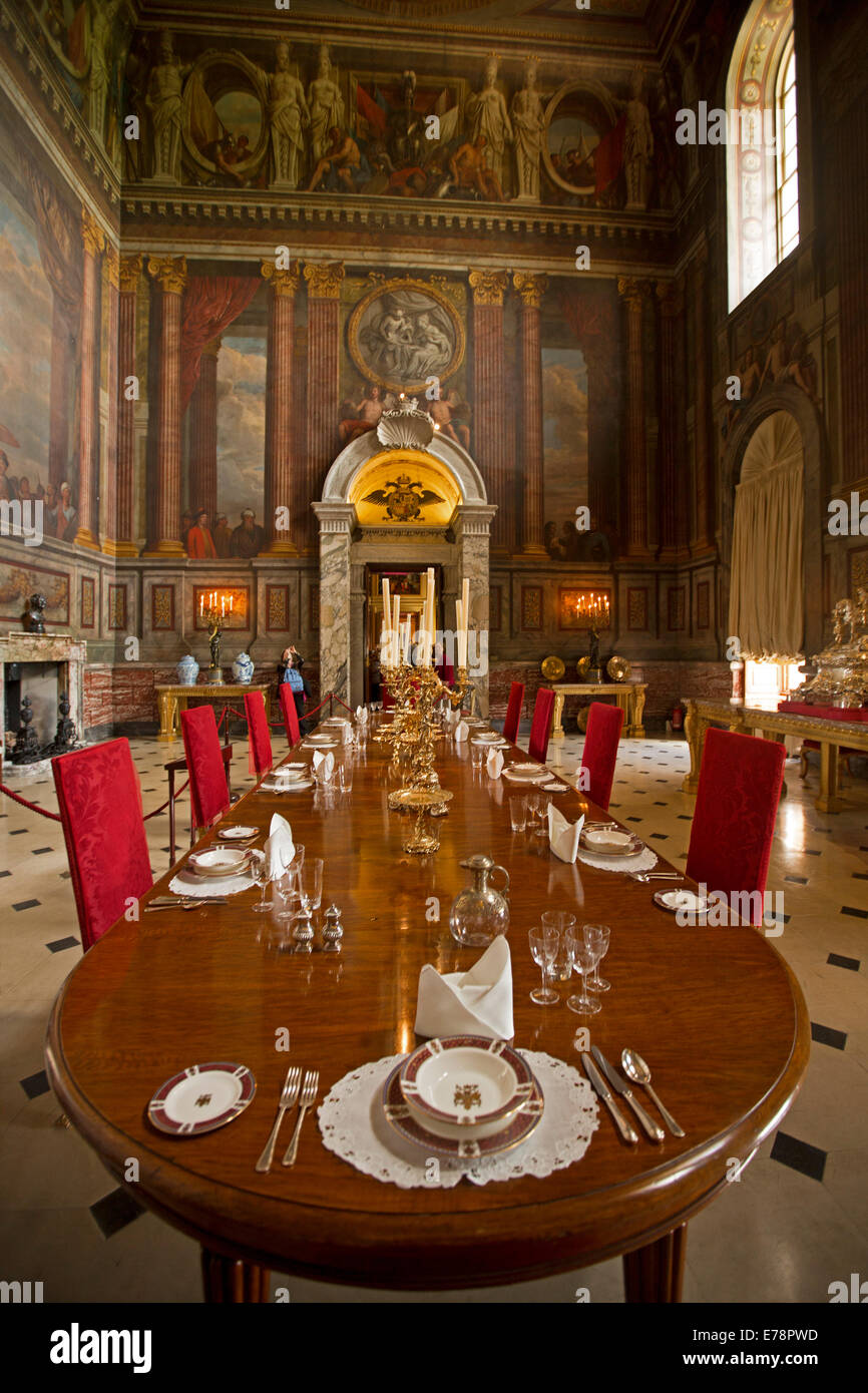 Grand et l'immense salle à manger avec grande table, fauteuils en velours rouge, de magnifiques peintures murales sur les murs élevés à Blenheim Palace Angleterre Banque D'Images
