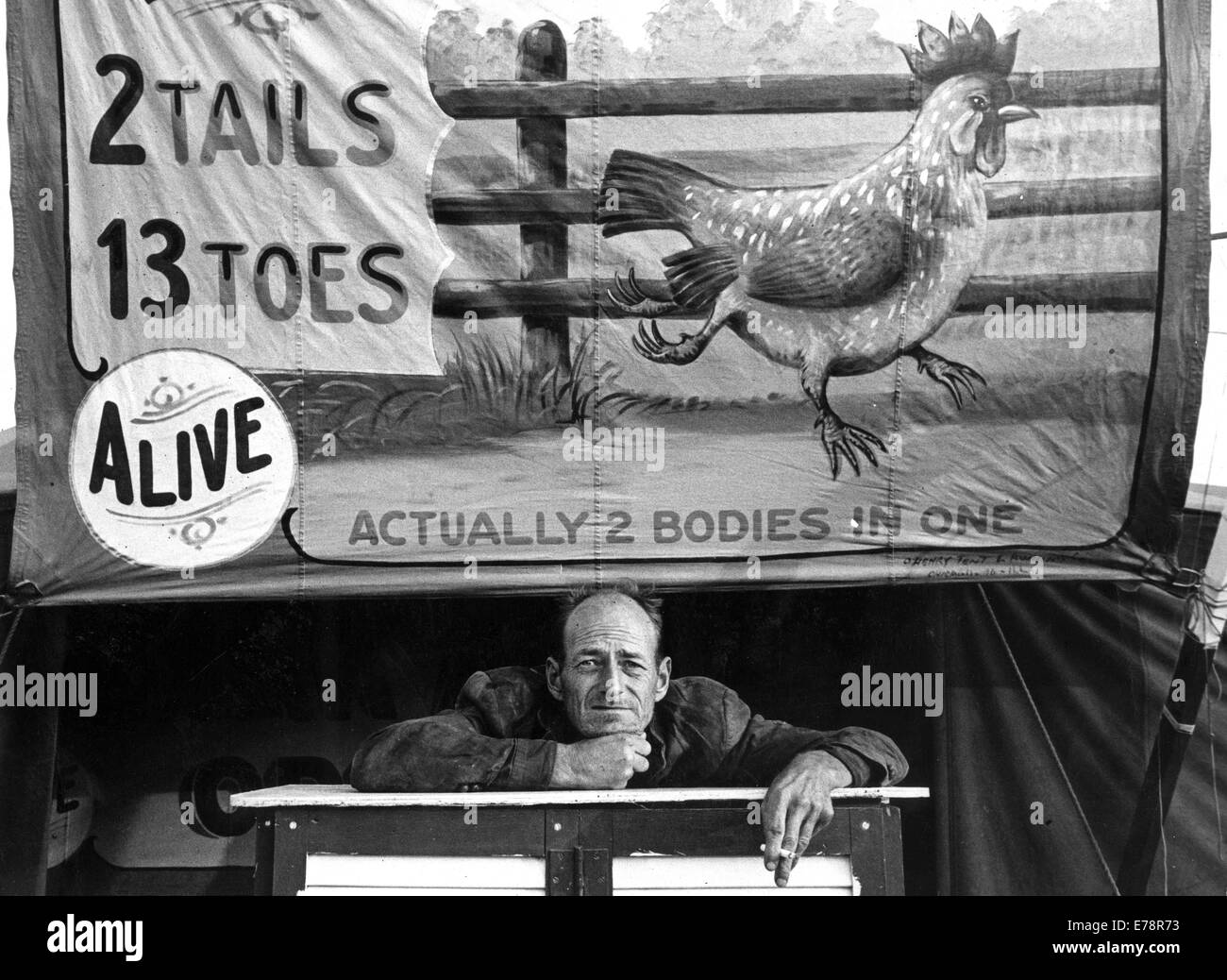Usa. 3e Mar, 1958. Date et lieu inconnu. Un homme est assis à un carnie stand devant une grande toile de signer la publicité d'un oiseau vivant avec 2 queues et 13 orteils à un parc d'amusement. © Burk Uzzle/KEYSTONE Photos/ZUMAPRESS.com/Alamy Live News Banque D'Images