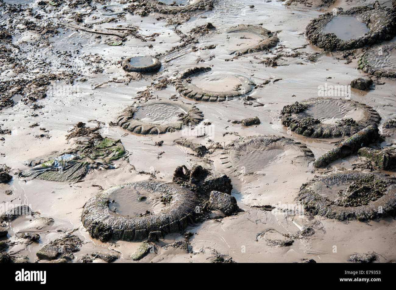 Pneus enfouis dans la boue des pneus de la pollution sous-évaluées de plage Banque D'Images