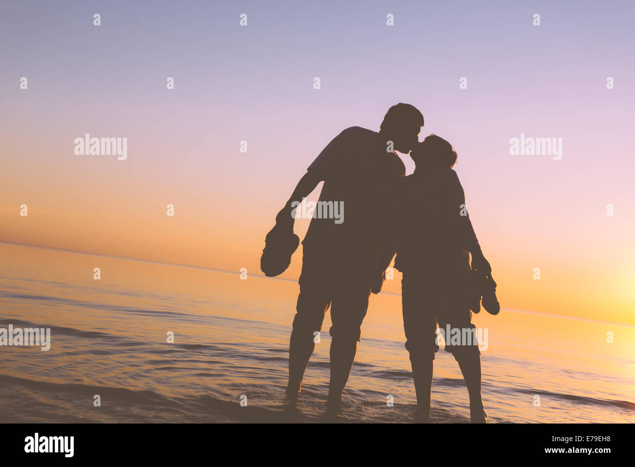 Happy senior couple silhouettes sur la plage s'embrasser Banque D'Images