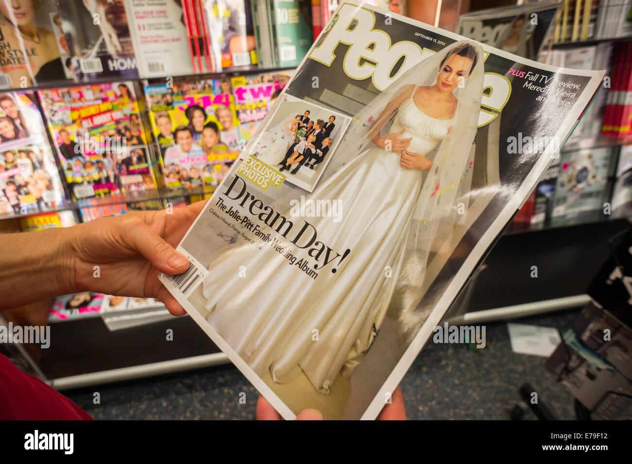 Le lecteur parcourt une copie de la revue People avec le mariage d'Angelina Jolie et Brad Pitt à New York Banque D'Images