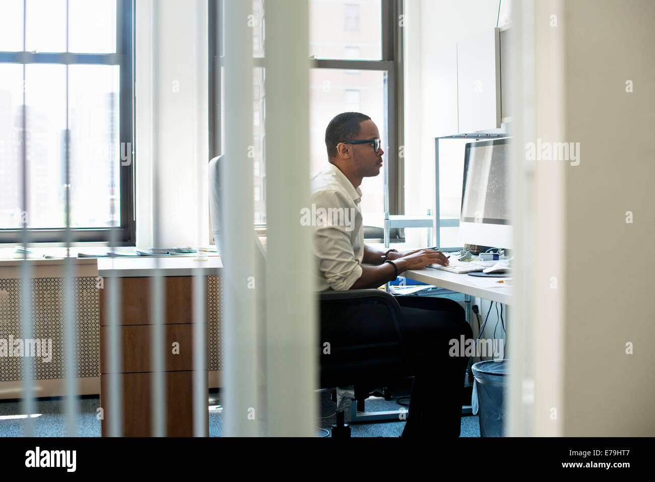 Un homme travaillant dans un bureau assis à un bureau. Regarder un écran d'ordinateur. Banque D'Images