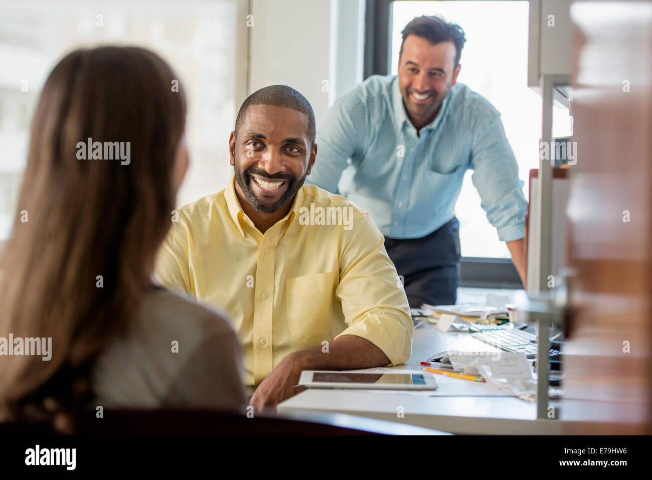 Trois personnes dans un bureau, deux hommes et une femme avec le moniteur de l'ordinateur et tablette numérique. Banque D'Images