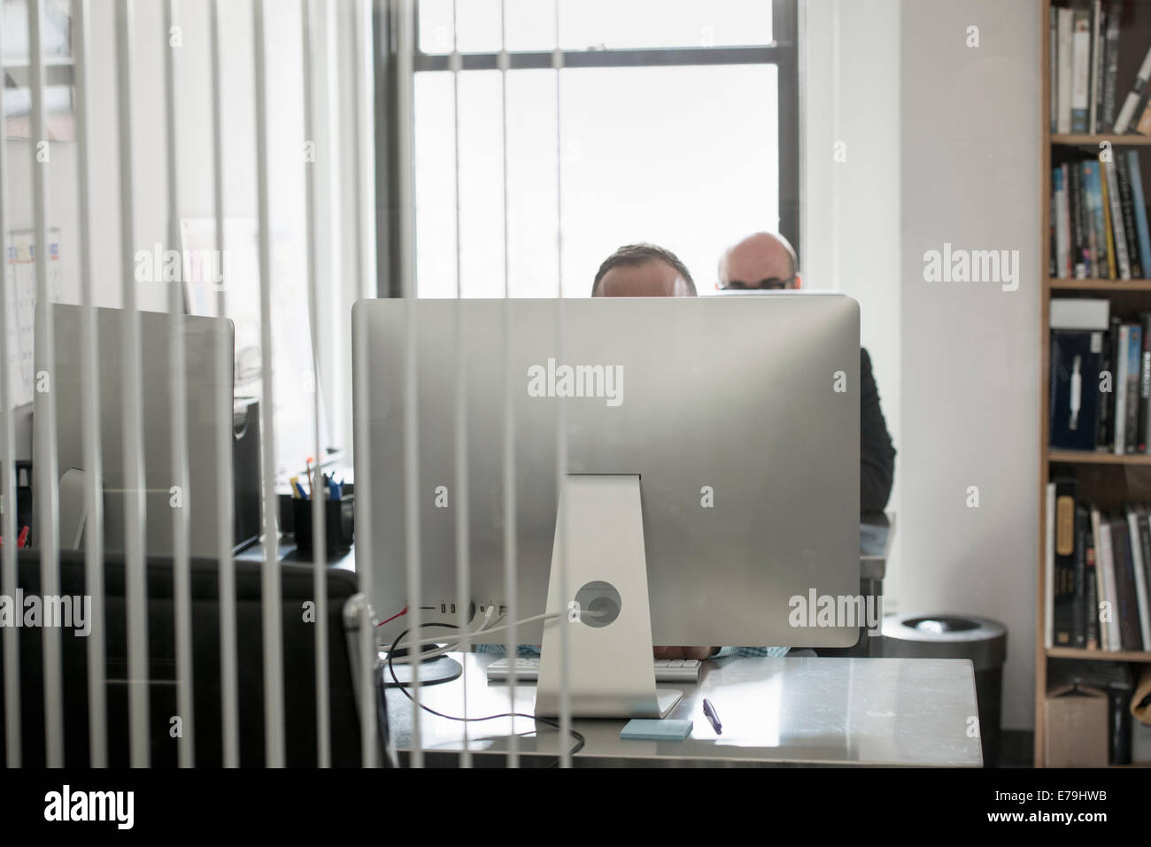 La vie de bureau. Deux personnes assises à un bureau derrière un ordinateur. Banque D'Images