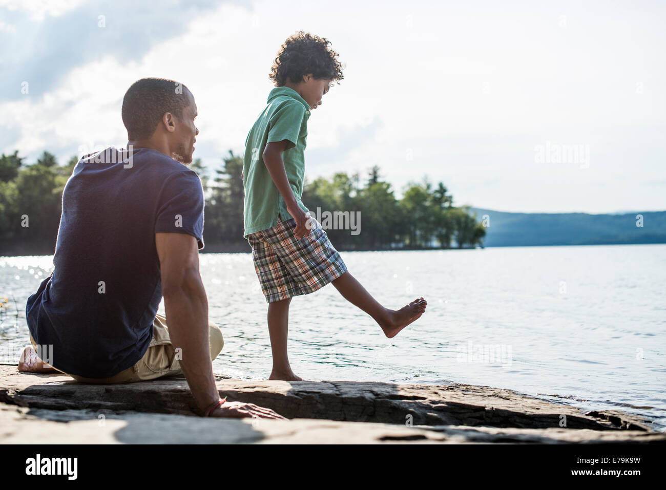 Un père et son fils, sur une rive du lac en été. Banque D'Images