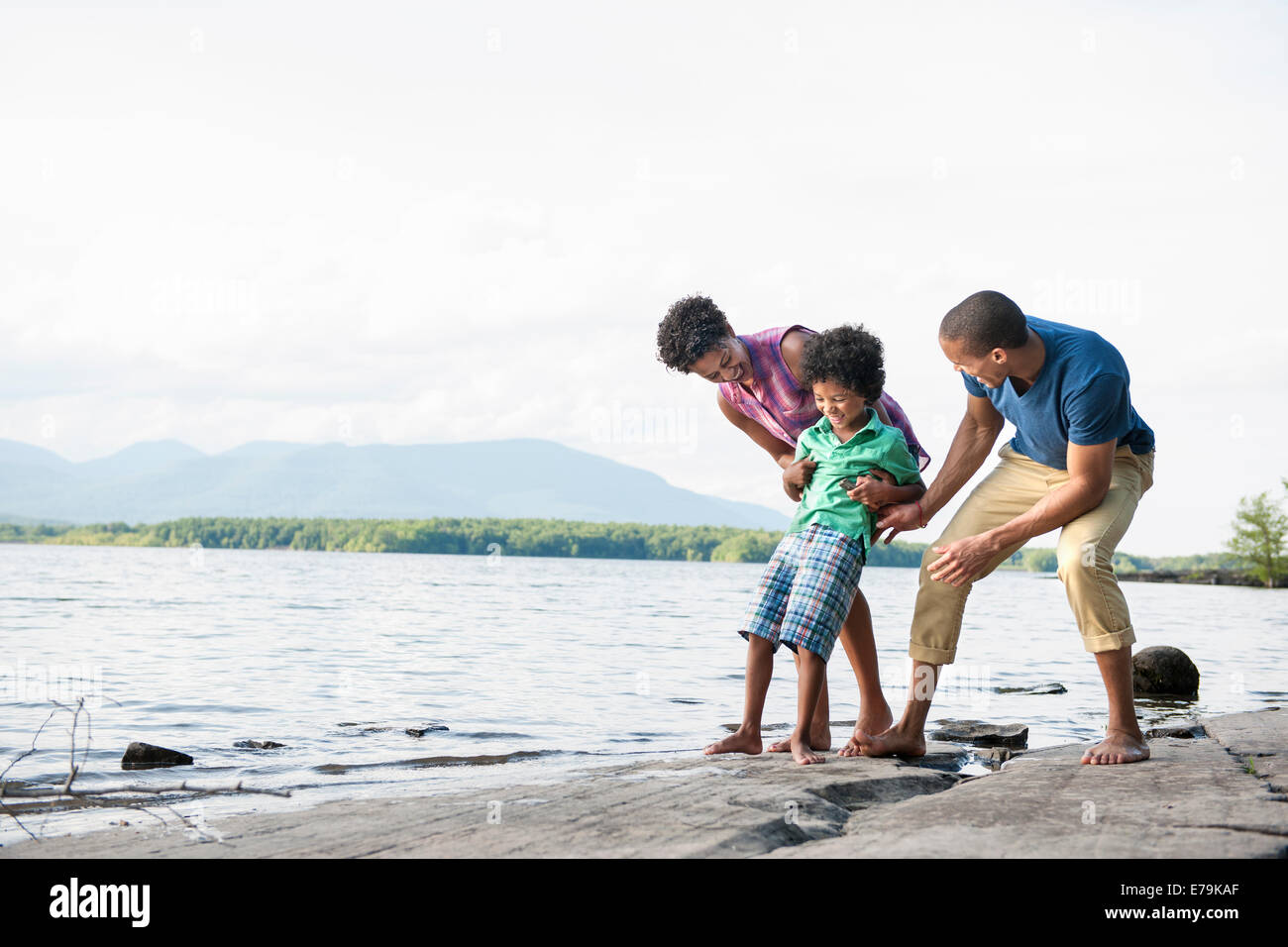 Une famille, mère, père et fils jouent sur les rives d'un lac. Banque D'Images