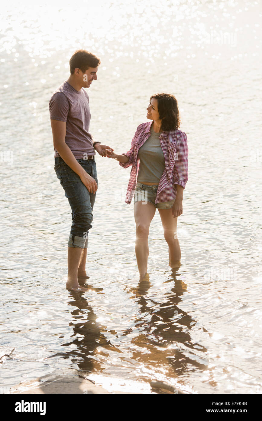 Un couple holding hands, pagayer en eau peu profonde au bord du lac. Banque D'Images