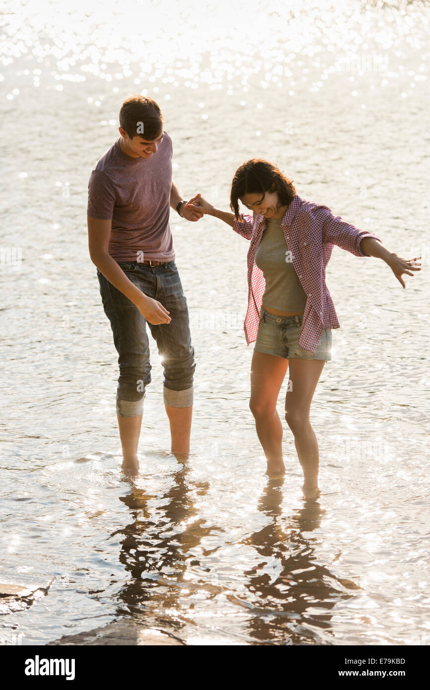 Un couple holding hands, pagayer en eau peu profonde au bord du lac. Banque D'Images