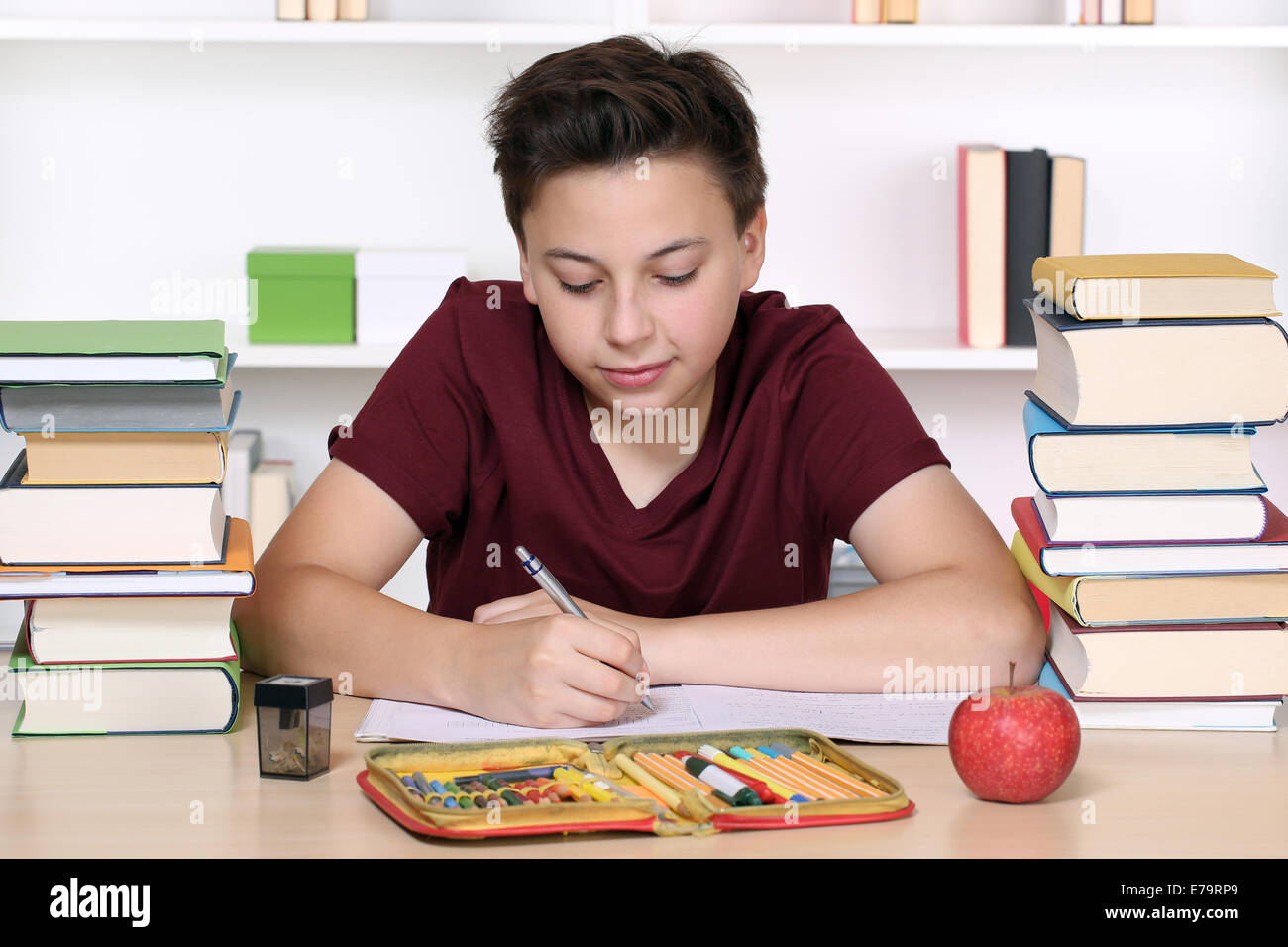 Jeune garçon écrit ses devoirs à l'école dans un livre d'exercice Banque D'Images