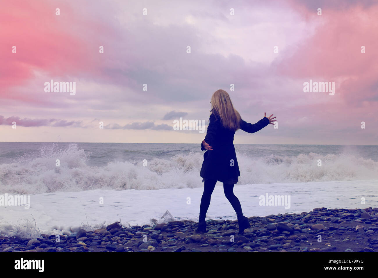 Jeune femme dans un manteau noir et un chapeau sur la plage Banque D'Images