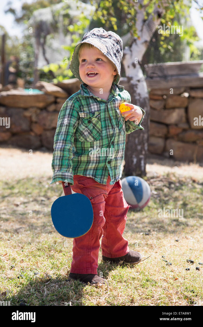 Happy boy holding tennis de table raquette et balle en park Banque D'Images