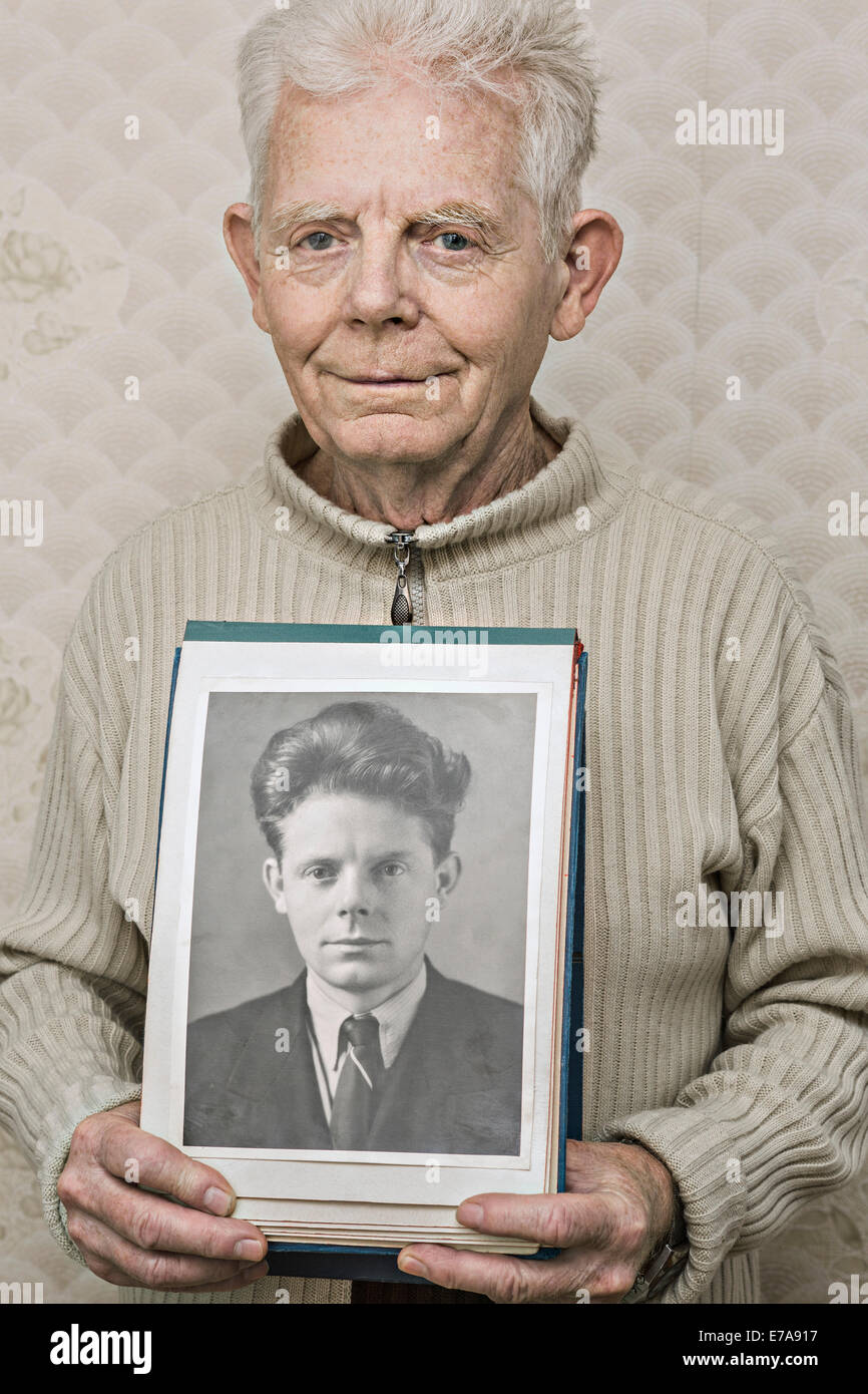 Portrait of happy senior man showing photo de lui-même dans sa vingtaine Banque D'Images