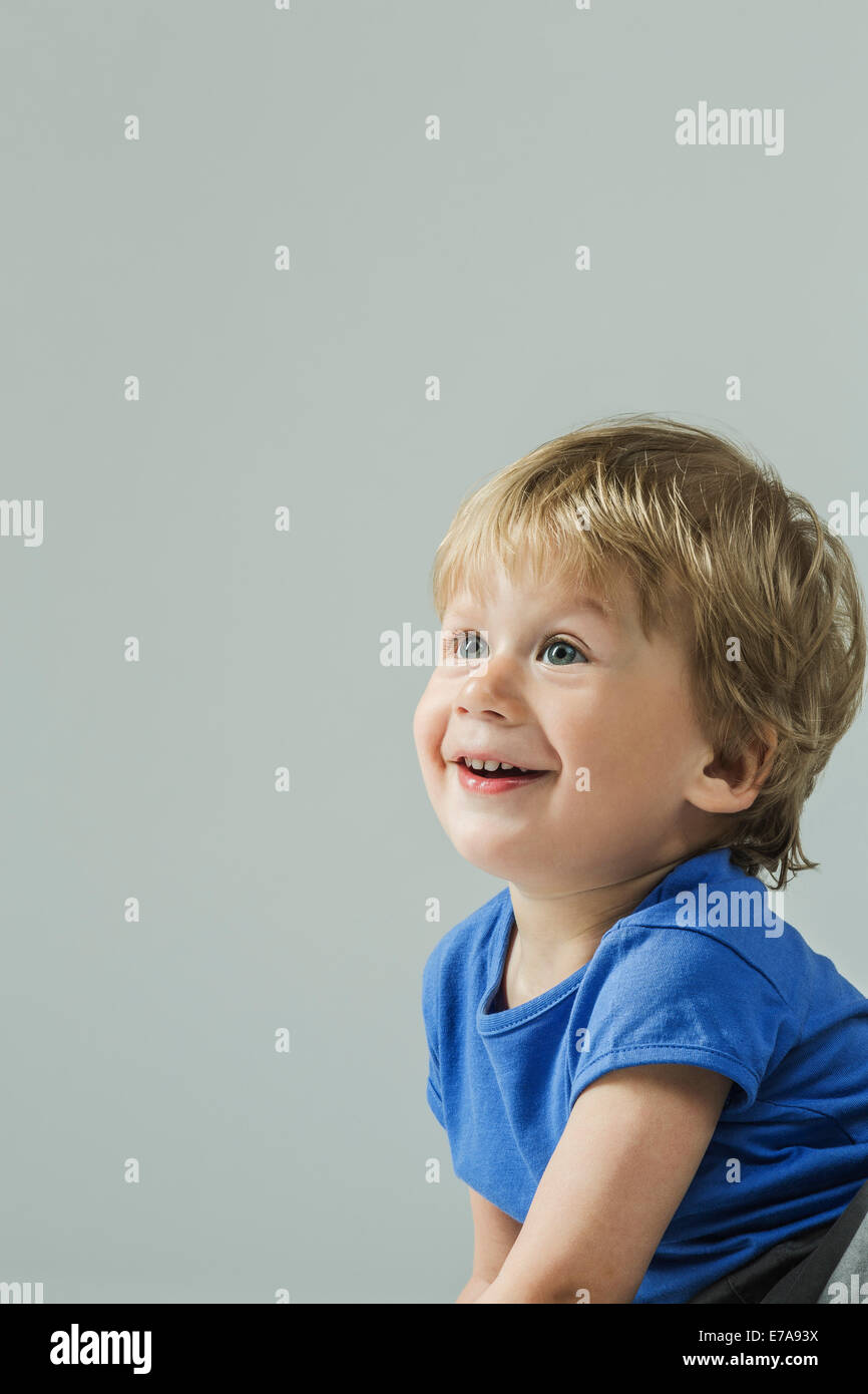Smiling baby boy looking away sur fond gris Banque D'Images