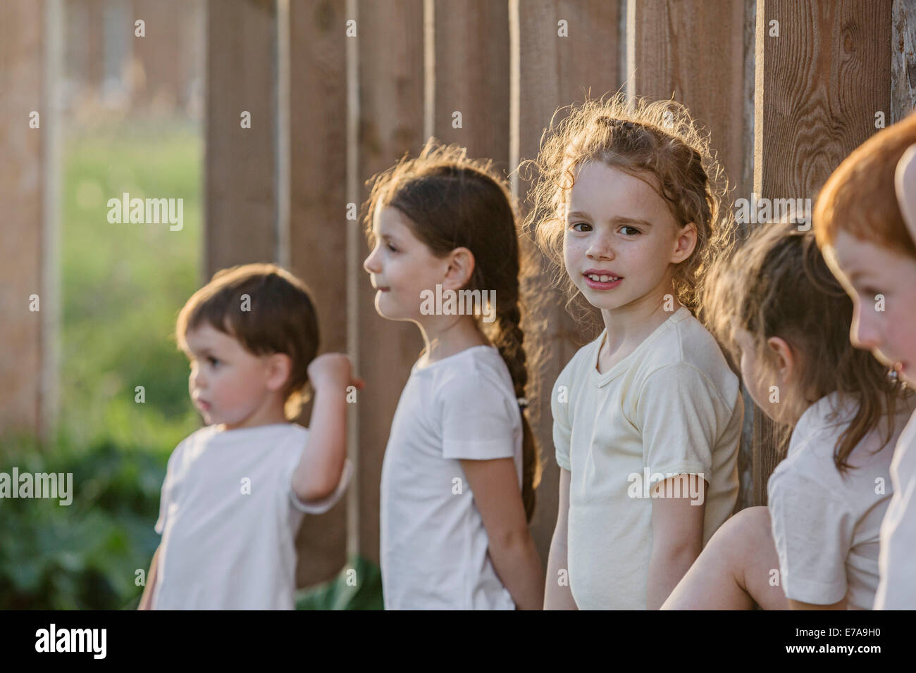 Portrait of cute girl standing avec vos amis contre la paroi en bois dans la région de park Banque D'Images