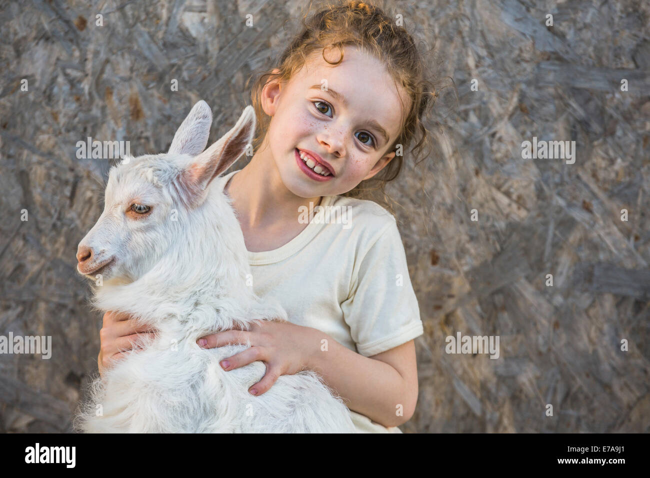 Portrait of cute girl holding baby goat outdoors Banque D'Images