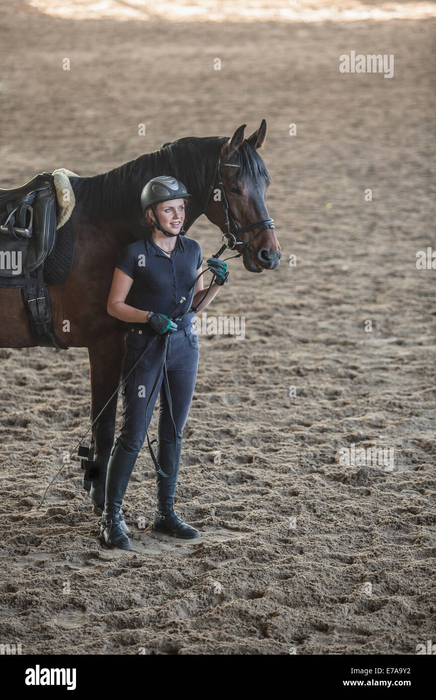 Toute la longueur de femme debout à cheval en training stable Banque D'Images
