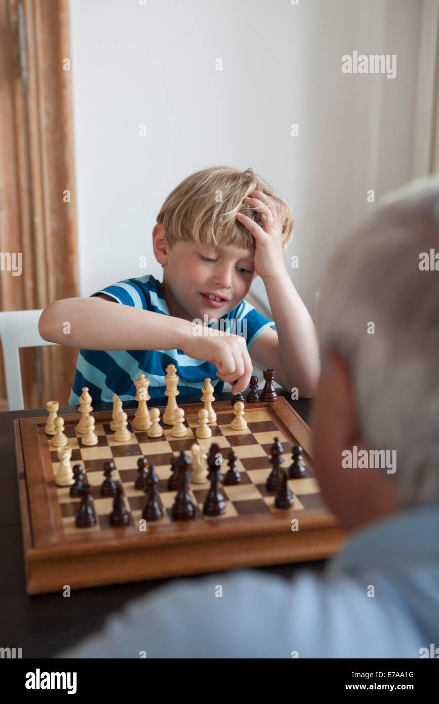Petit Garçon jouant aux échecs avec son grand-père à la maison Banque D'Images
