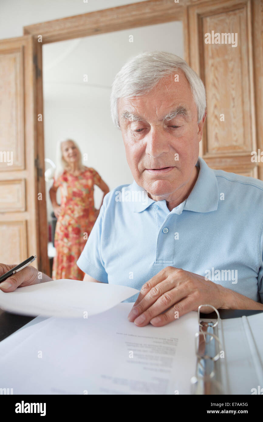 L'examen des documents financiers Senior homme femme avec en arrière-plan à la maison Banque D'Images