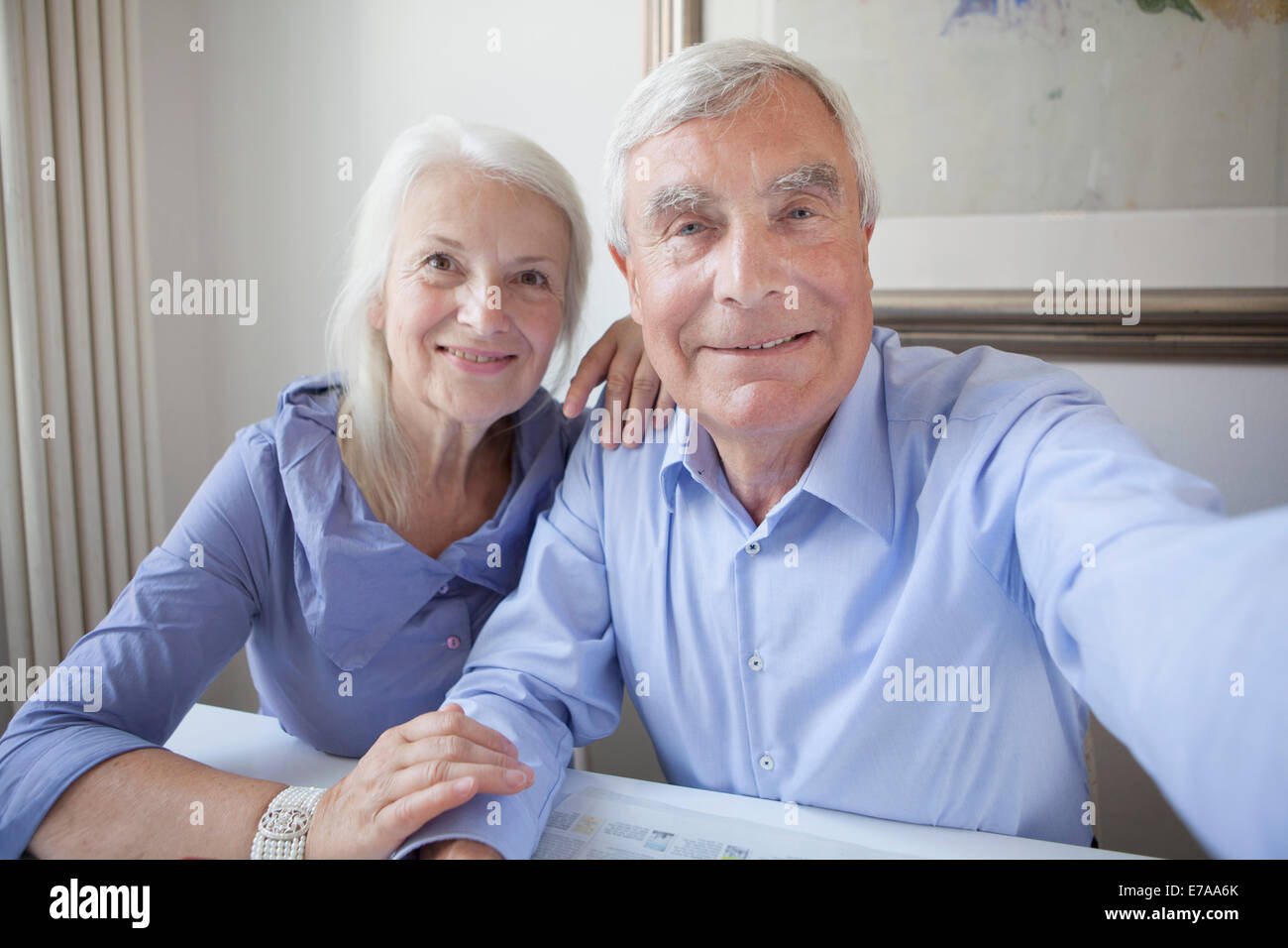 Portrait of smiling senior couple sitting at table in house Banque D'Images